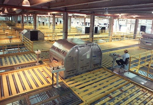 A large shipping container with FedEx branding in a warehouse-like facility with yellow carts and pallets.