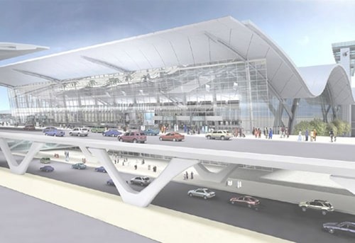 Modern airport terminal with dramatic architecture, busy with vehicles and pedestrians.