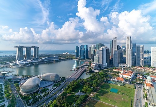 Aerial view of the modern skyline of Singapore, with the iconic Marina Bay Sands hotel, central business district, and surrounding waterfront.