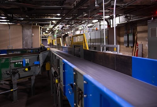 Dimly lit industrial interior with cargo containers and equipment, suggesting a warehouse or shipping facility.