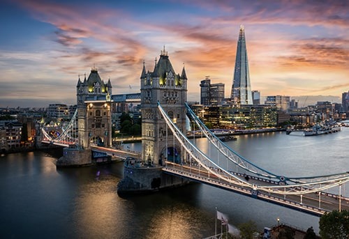 Vibrant cityscape of London at sunset, featuring Tower Bridge, The Shard, and other iconic landmarks along the River Thames.