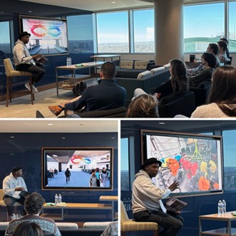 A group of people in a conference room, gathered around a large screen displaying a map with various routes and traffic markers.