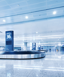 Luggage carousel in airport terminal with Gate 36 sign and bright lighting.